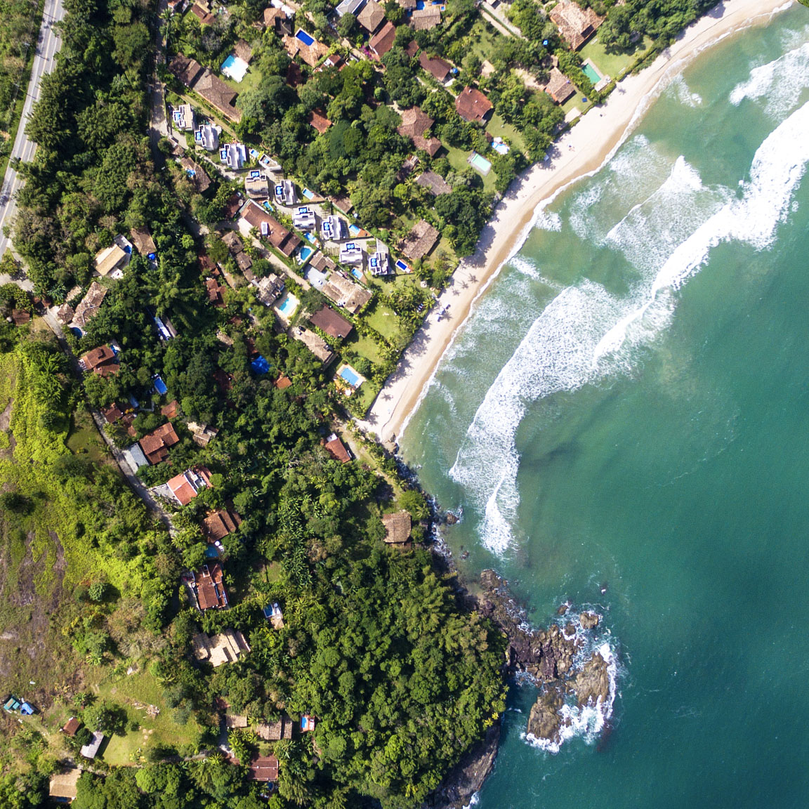 Aerial image of buildings, homes, and green trees along a coastline and blue ocean