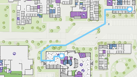 Digital map with square buildings, green trees, and a route highlighted in blue showing wayfinding around a large campus