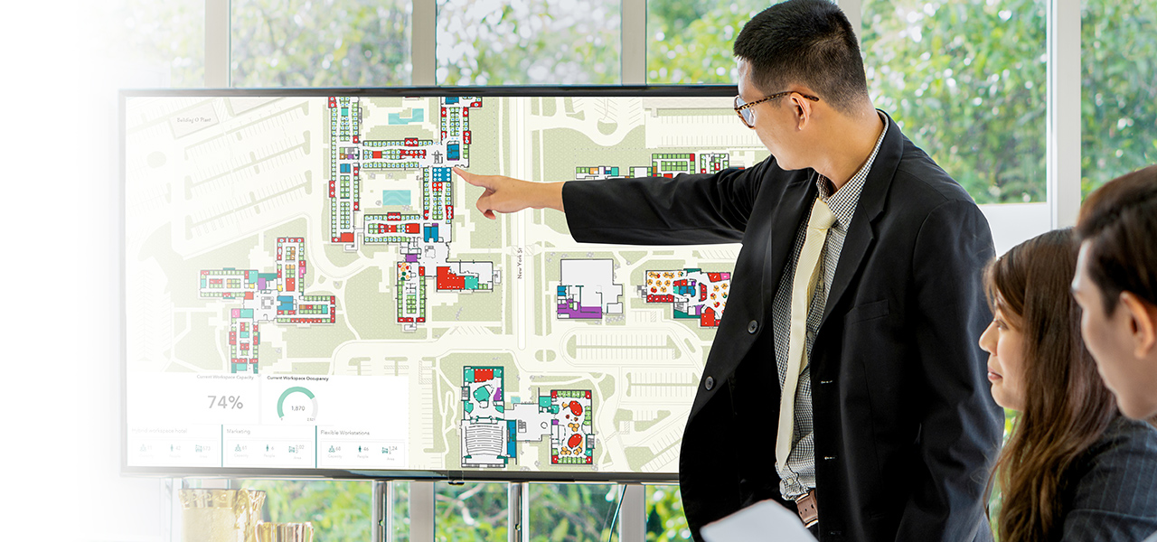 Executive showing his team a campus map with an indoor space planning interface and dashboard to plan space use