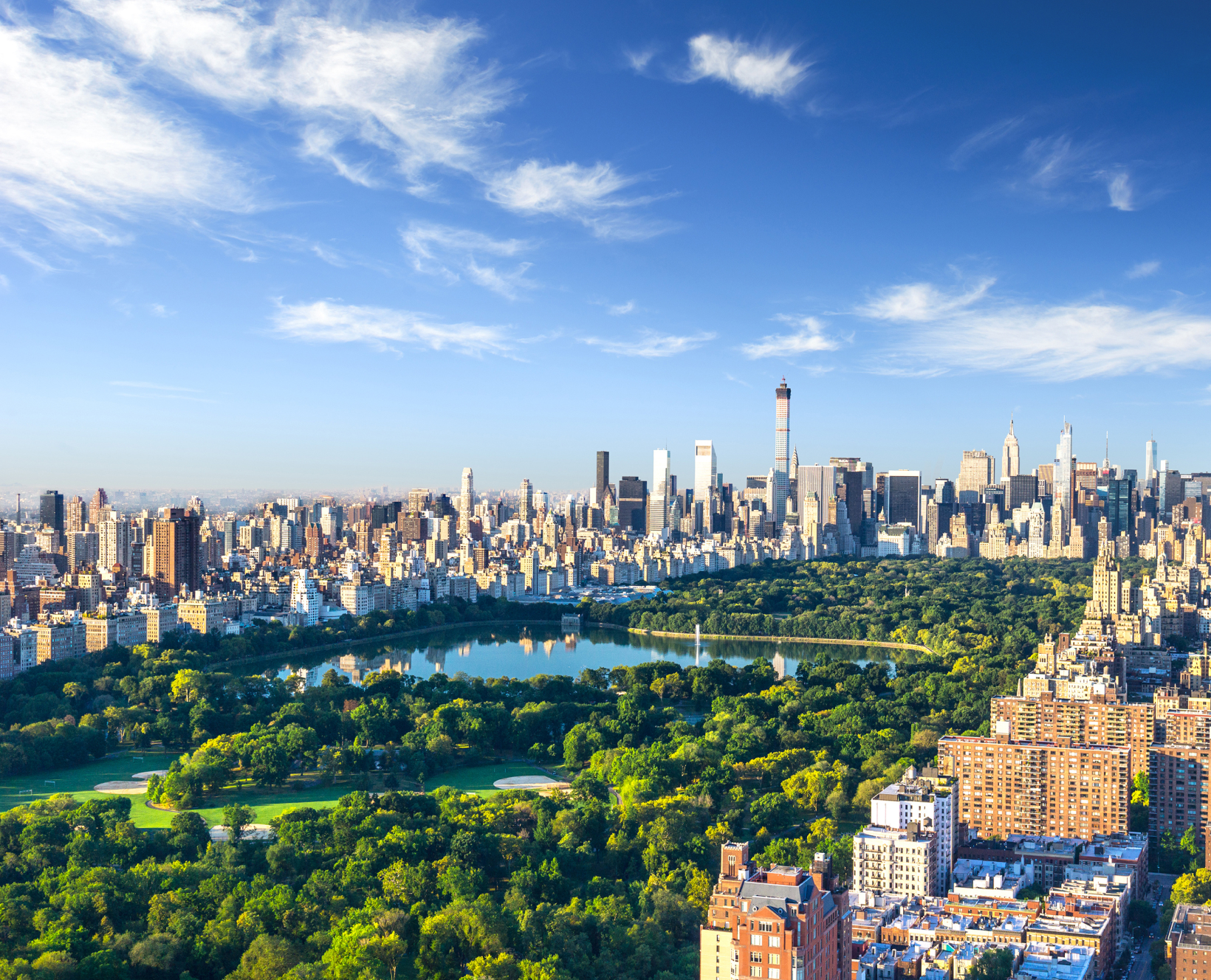 A picture of Central Park and the New York City skyline showing buildings, green trees, and a blue sky