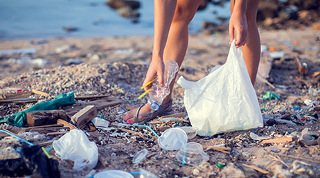 Woman picking up trash on a beach