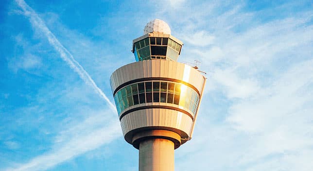 An air traffic control tower with many windows against a blue sky