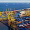 An expansive shipping port with numerous cargo containers and cranes, situated by the sea.