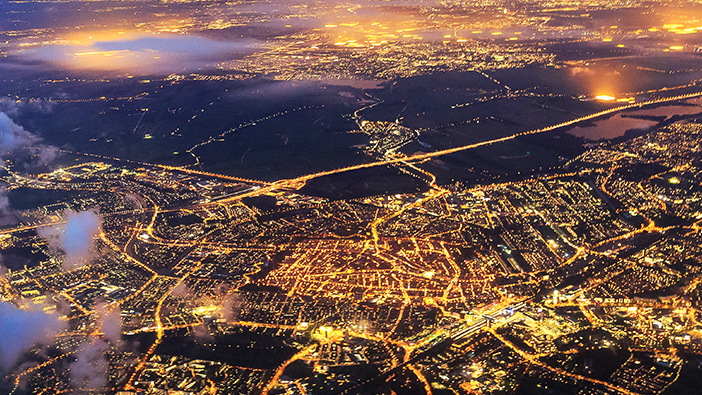 Image d'une ville la nuit avec des lumiaires jaunes claires et un pont qui enjambe une eau bleue