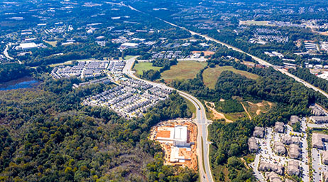 An aerial view of Johns Creek, Georgia, with a highway running through developed areas surrounded by trees