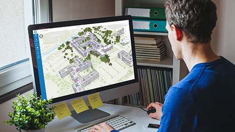 Person in home office looking at computer monitor displaying ArcGIS Indoors Viewer