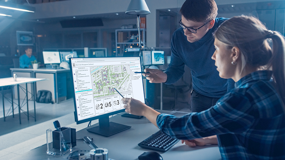 Un hombre y una mujer mirando un cuadro de mando de cartografía de interiores en la pantalla de un ordenador de escritorio para supervisar el estado del edificio