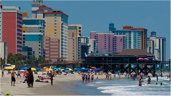 Beach crowded with people and multicolored buildings along the shoreline