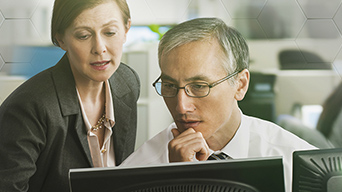 Man and a woman in an office looking at a computer monitor