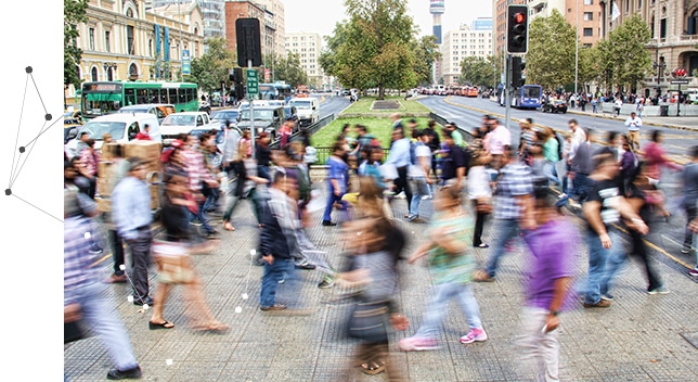 A crowd of people crossing a car-filled road using a city crosswalk