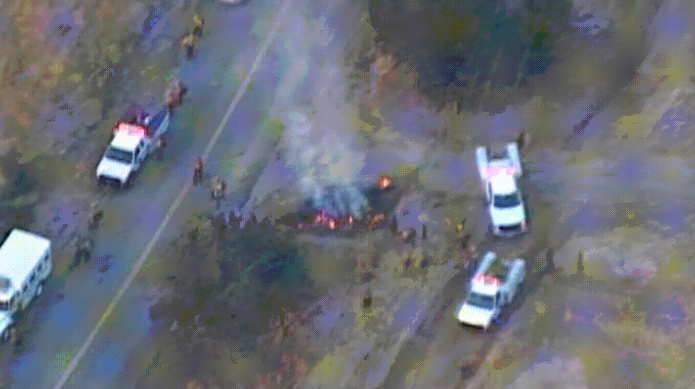 Drone footage of a fire on a highway with emergency response vehicles