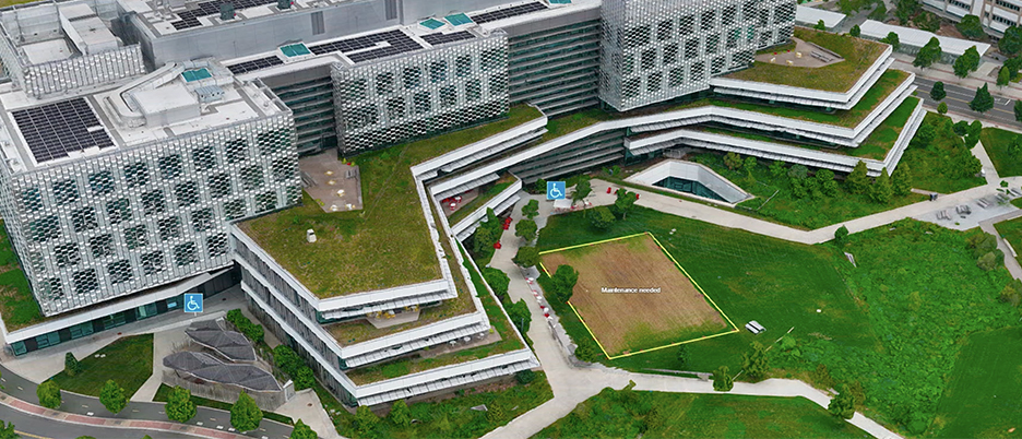 An aerial image of a large modern university campus with wide tiered green lawns