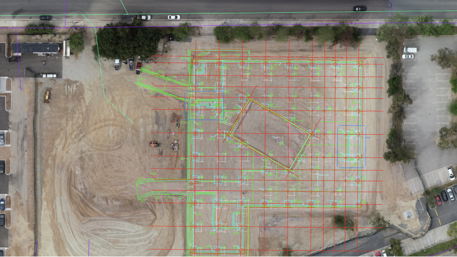 Drone image of a construction site for a building with a green and red grid representing building information modeling 