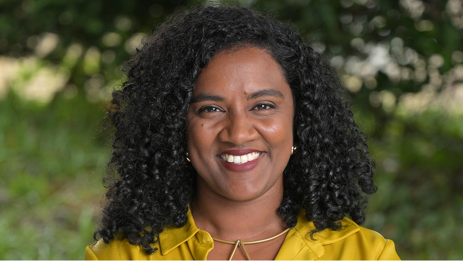 Véronique Couttee smiling in front of green foliage in soft focus