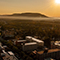 An oblique aerial view of State College, Pennsylvania, at sunset with college and residential buildings and forest and mountains in the distance