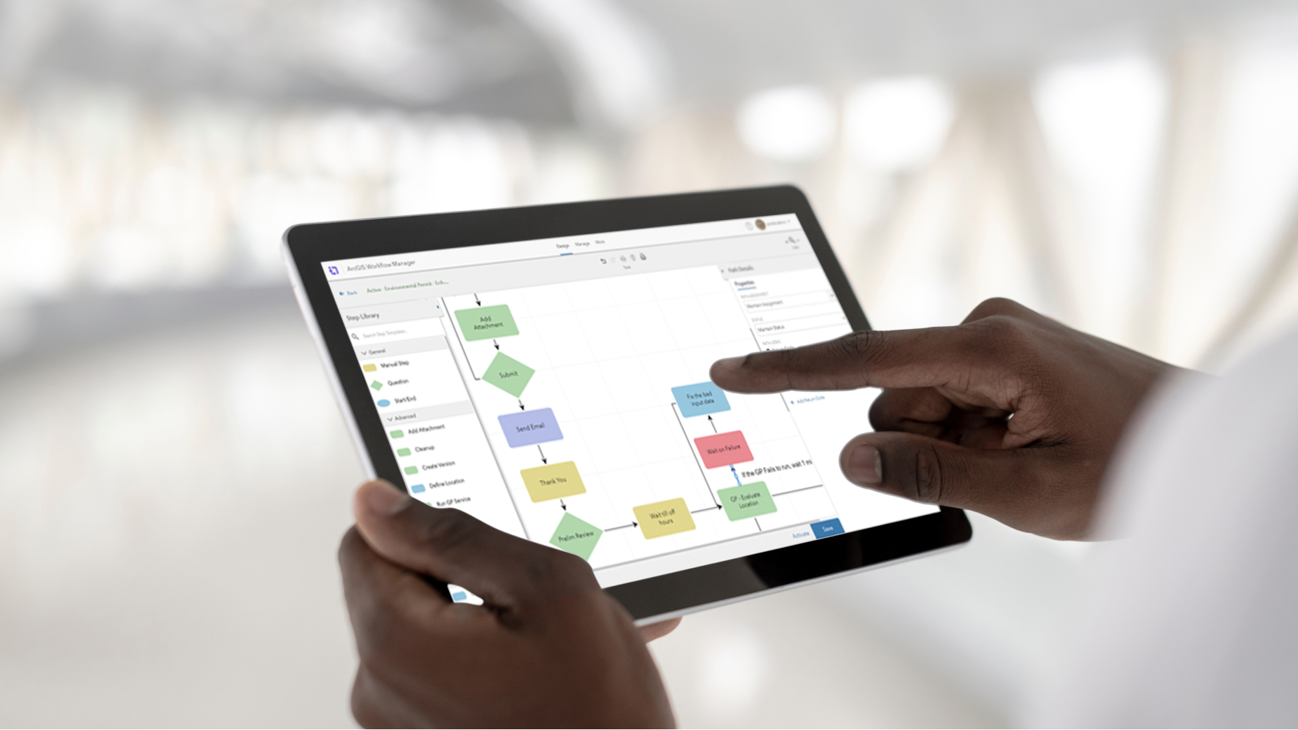 Person holding a tablet that is showing multicolored boxes connected by arrows representing a flowchart