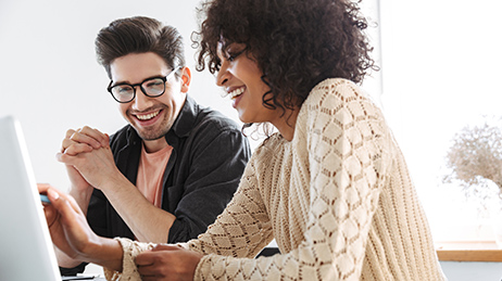 Two people looking at a monitor. One of them is interacting with the touch screen.