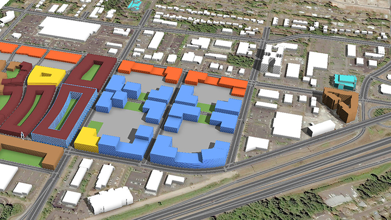 An aerial view of multiple blocks of digitally modeled buildings highlighted in different colors next to a railroad 