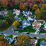 An aerial image of a cul-de-sac neighborhood with tidy white houses and many autumnal trees