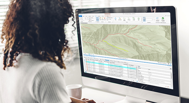 Woman looking at a computer screen displaying a map with table showing detected errors 