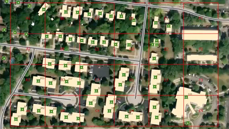 Aerial photo of a neighborhood with map points over individual buildings overlaid with a red grid