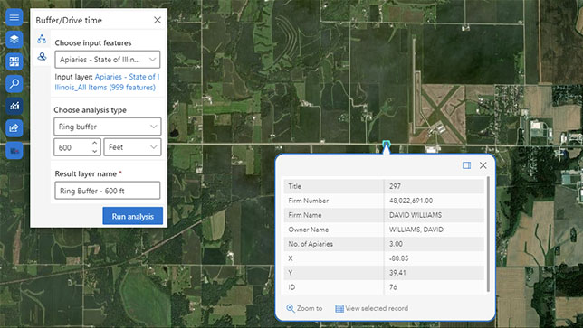 Satellitenbild einer grünen Landfläche, auf dem weiße Pop-up-Felder mit Text zu sehen sind. Die Felder stellen einen Puffer-/Fahrzeit-Layer und eine Feature-Auswahl dar.