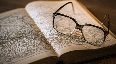 A pair of reading glasses resting on top of an open map book