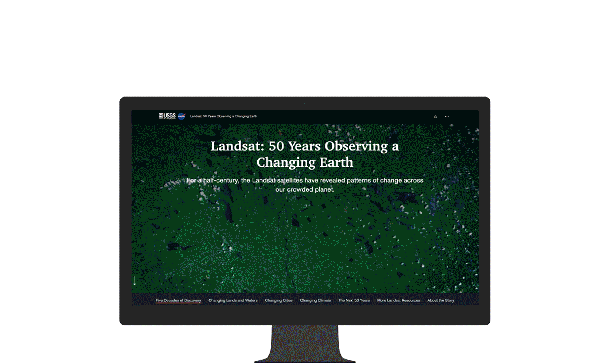 テキスト付きの記事と、Landsat 衛星から取得した陸地の航空写真を表示するコンピューター モニター