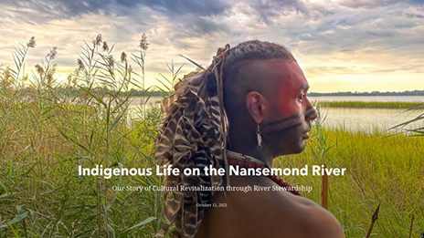 Native male with face painting and headdress looking out on the river in grasslands 