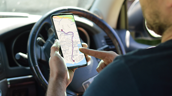 A person in a car looking at routing direction on a mobile device 