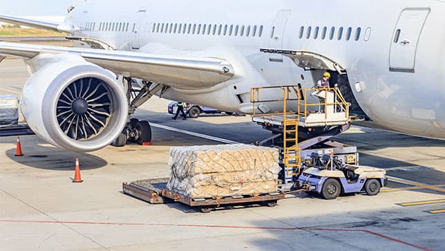 A worker unloading a large shipment from an airplane