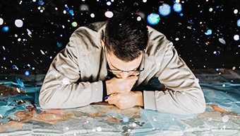 A young man with glasses looking down at a large worldwide map