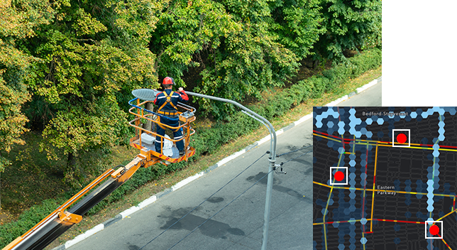 A photo of a utility worker using an aerial work platform to reach a streetlight, overlaid with a street heat map