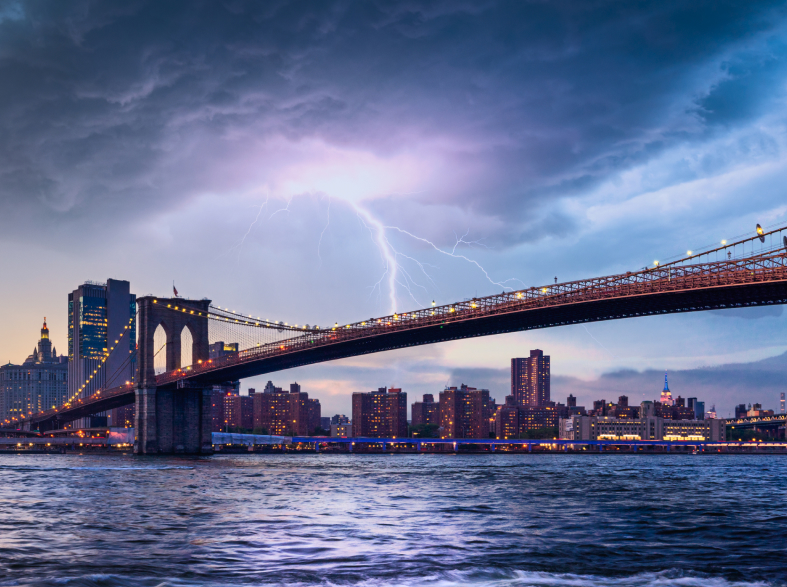 A bridge in New York City during a thunderstorm with lightning coming down from a dark cloud