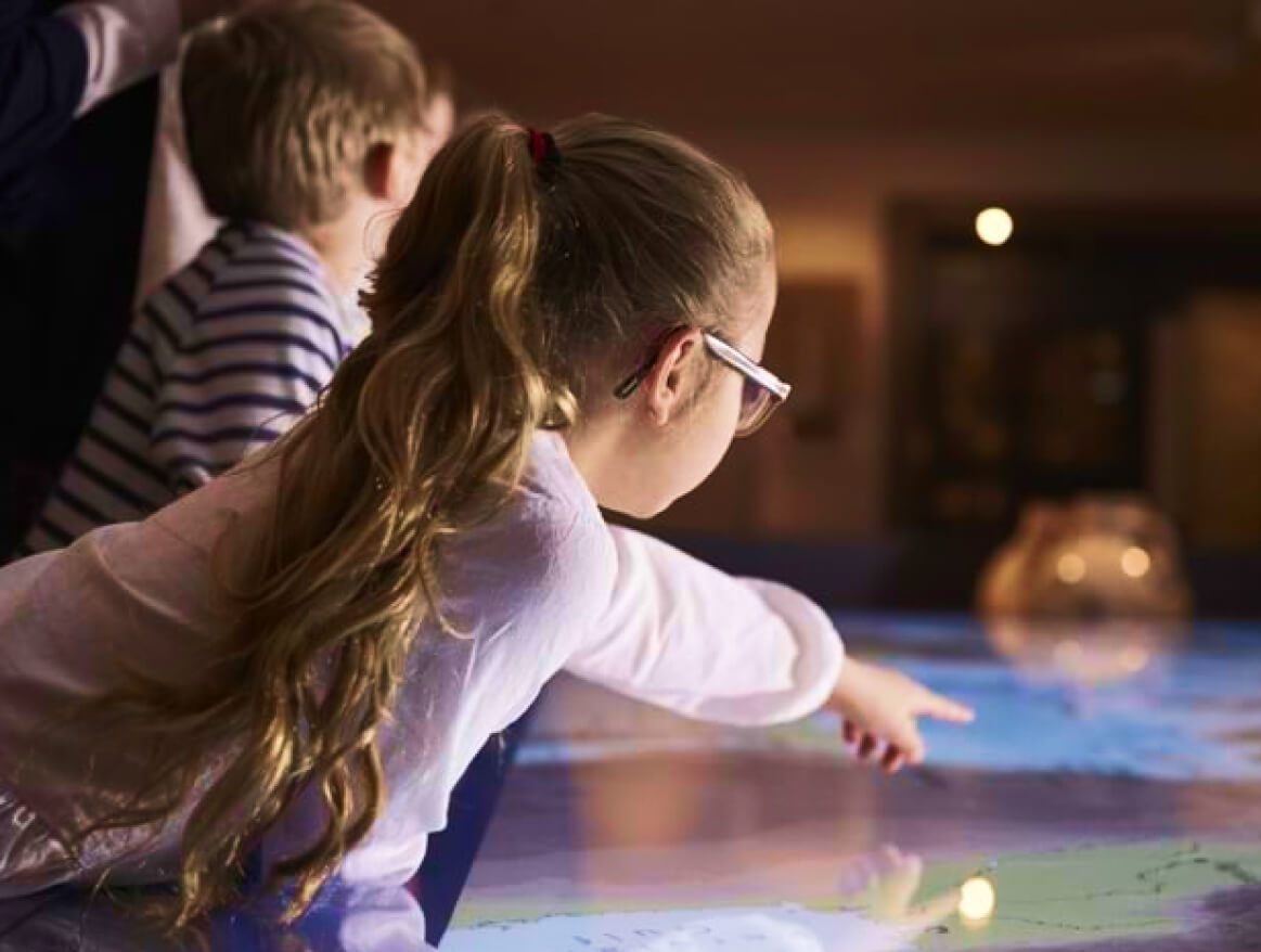 A child pointing at a digital map displayed on a tabletop
