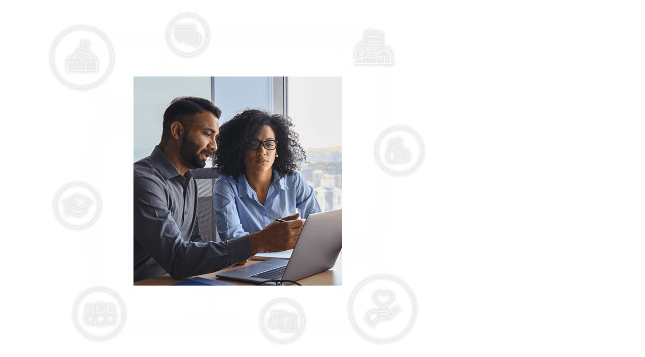 Two colleagues stare at a laptop, one of them points out some information on the screen