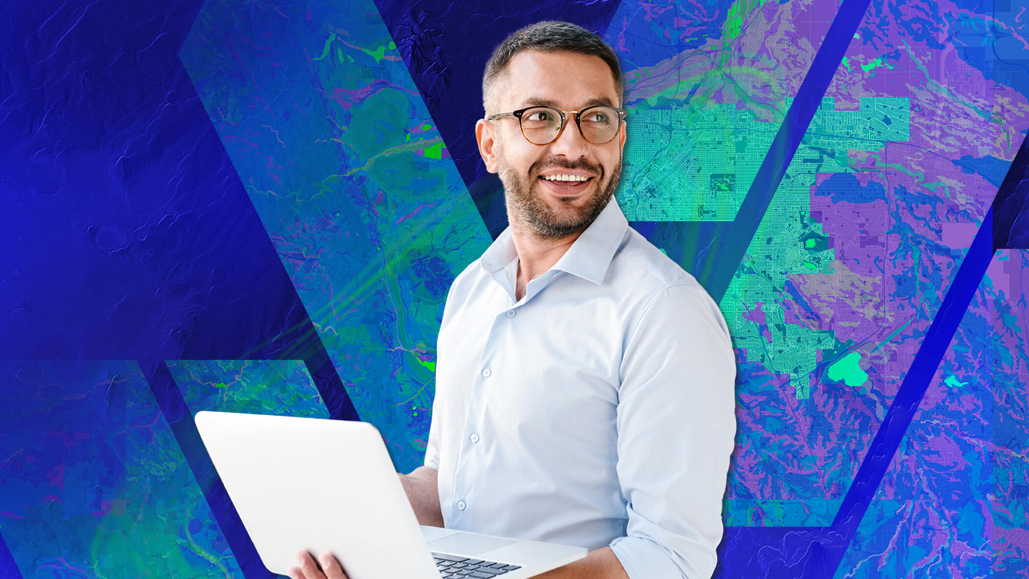A professional individual wearing glasses and a business casual shirt, smiling, and looking off to the side while holding a laptop