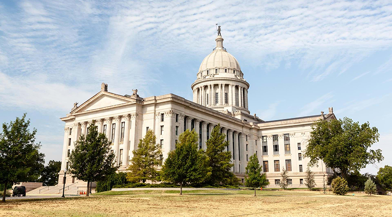 The Oklahoma State Capitol building with its domed roof and columns beneath a partly cloudy sky