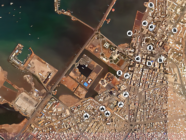 The view from a satellite of a coastal area with multiple map markers covering buildings on land