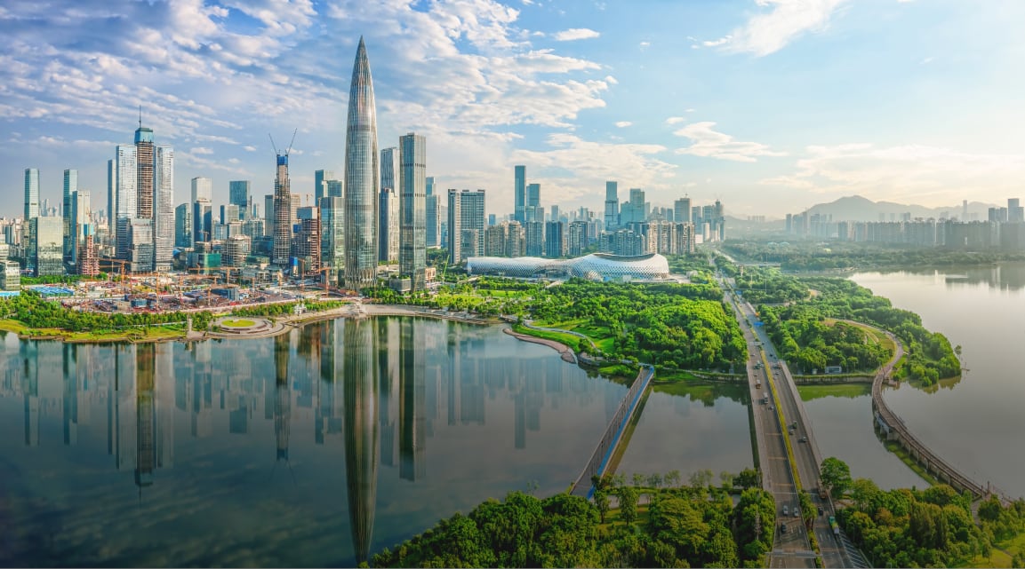A waterfront city of modern skyscrapers and dense infrastructure paired with lush greenery