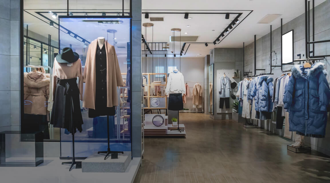 An upscale retail storefront with clothing displayed on mannequins in the window and more hanging clothing inside