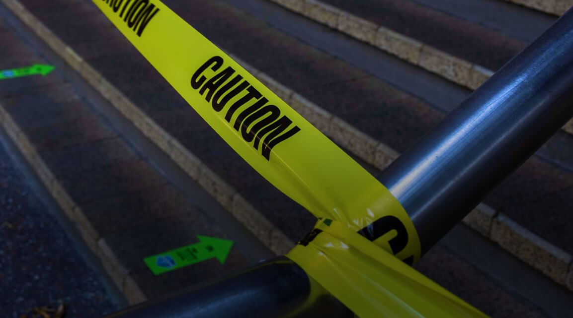 Closeup of caution tape blocking off an outdoor concrete stairway