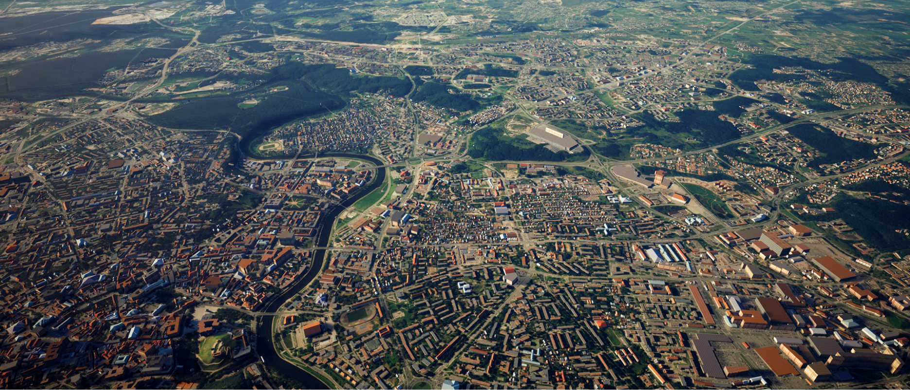 An aerial view of an expanse of developed land with a river snaking through