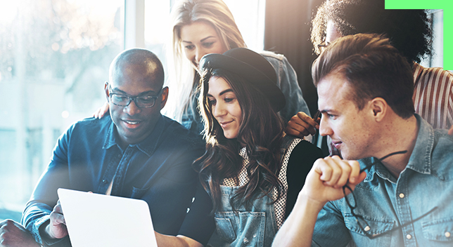 Diverse group of people gathered around a laptop