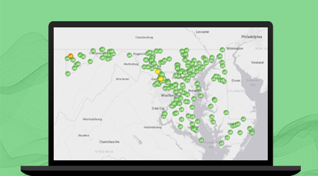 A laptop displaying a white map of the D.C., Maryland, and Virginia (DMV) area with many green circular icons marking the map 