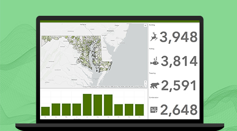 A laptop displaying a dashboard with a grey map marked in green, a green bar chart, and a number chart 