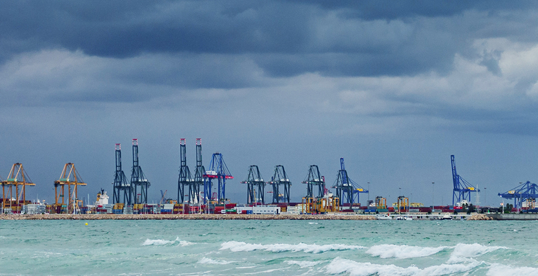 Panorama photo of the Port of New Orleans beside choppy green ocean waters beneath a dark blue stormy sky