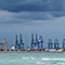 Panorama photo of the Port of New Orleans beside choppy green ocean waters beneath a dark blue stormy sky 