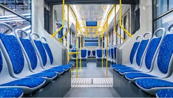 A view of the inside of an empty metro railcar with a bright yellow railing and blue and gray seats