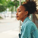 A person waiting for a bus at a roadside bus stop shelter